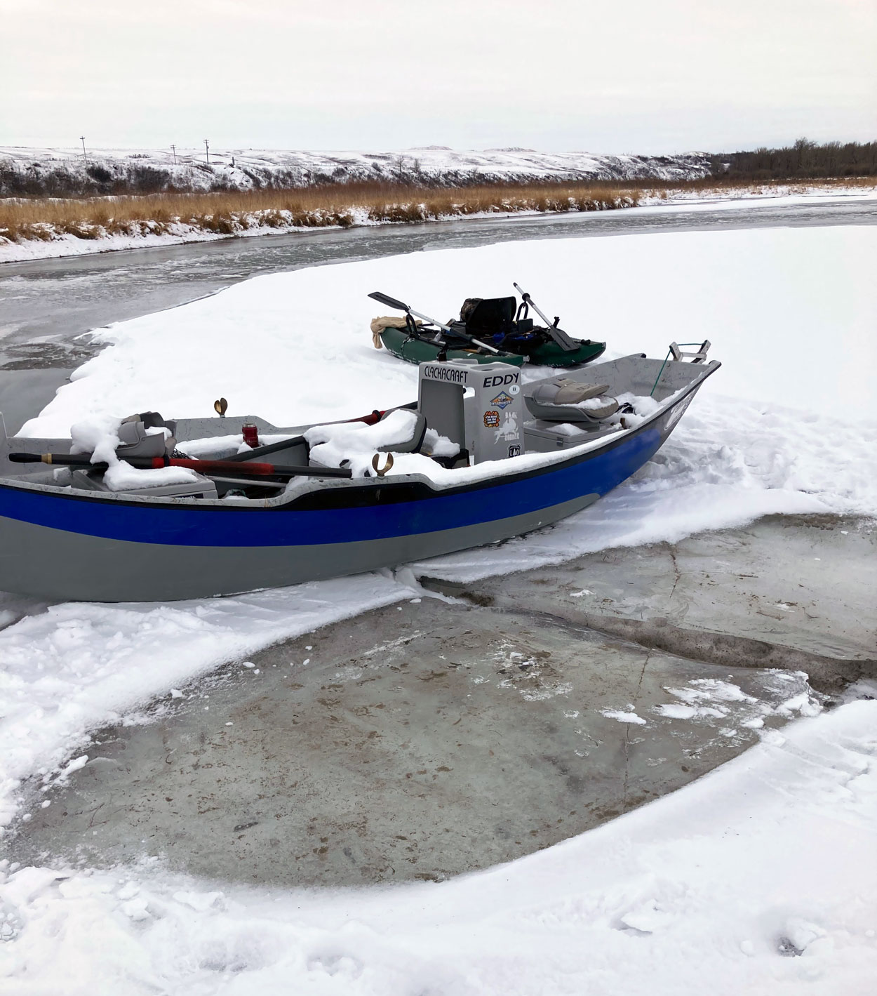 winter fishing float bow river drift boat in ice.