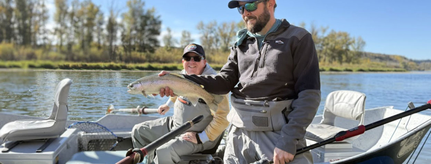 Angler landing a healthy rainbow trout on a guided Bow River drift boat trip.