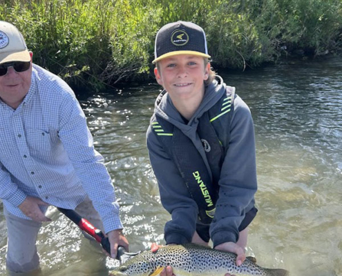 Youth angler catching a brown trout during a Bow River walk-and-wade trip.